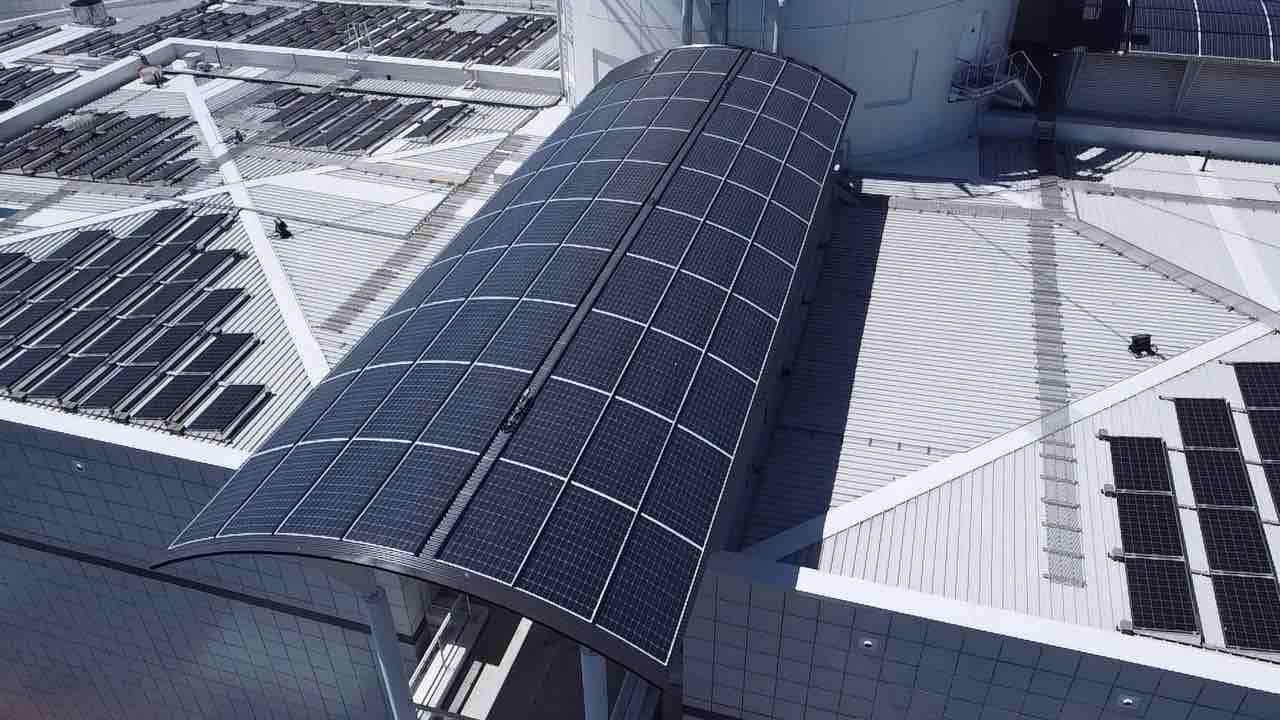 Overhead of a barrel-vault solar canopy and surrounding rooftop arrays on the square-tiled Questacon facade